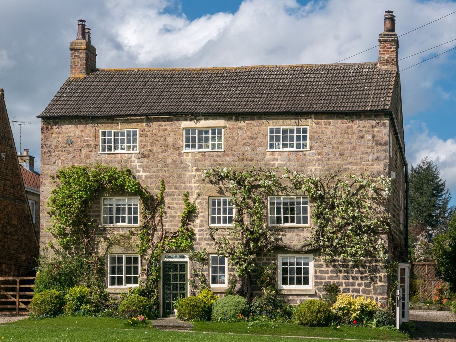 Traditional stone countryside house with ivy, a garden and warm natural textures