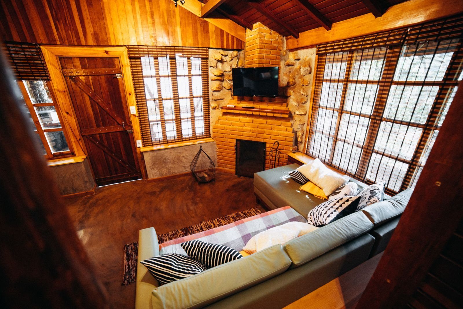 Warm timber-lined sitting room with a stone fireplace, soft seating and woodland light
