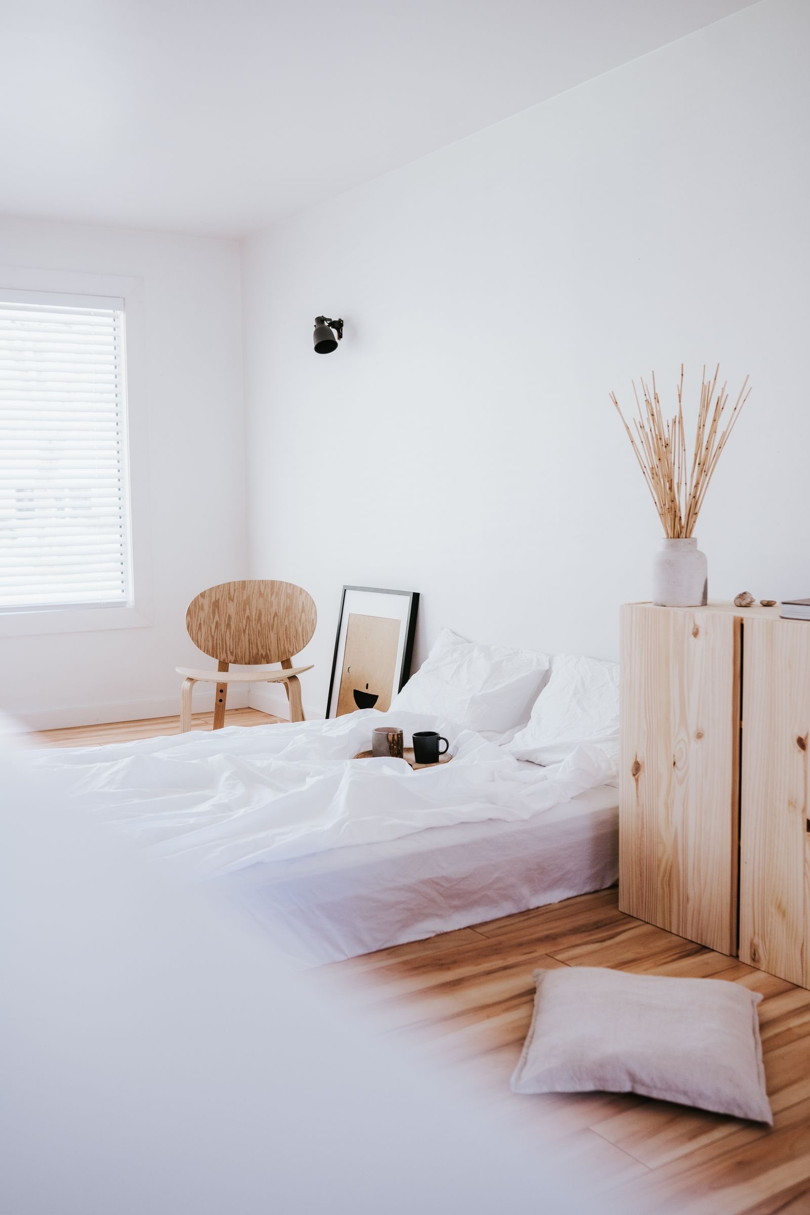 Quiet white bedroom with pale wood, simple furnishings and natural light